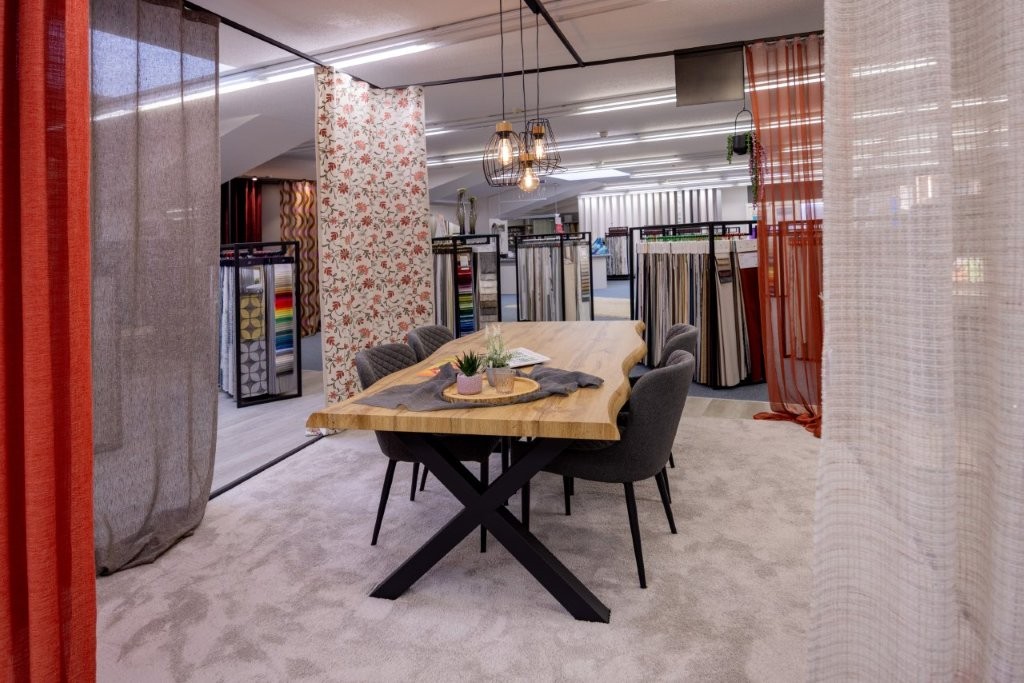 Gemütlicher Beratungsplatz im Showroom von Raumausstattung Storck in Bohmte mit Fokus auf textile Raumgestaltung: Hochwertige Vorhänge, Dekostoffe und flauschiger Teppichboden für ein modernes Wohnambiente.